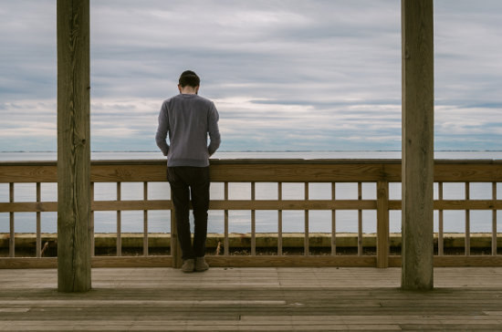 Mężczyzna stoi na drewnianym moście i spogląda w dal