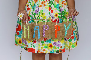 Dziewczyna w sukience trzyma plakietkę z napisem happy